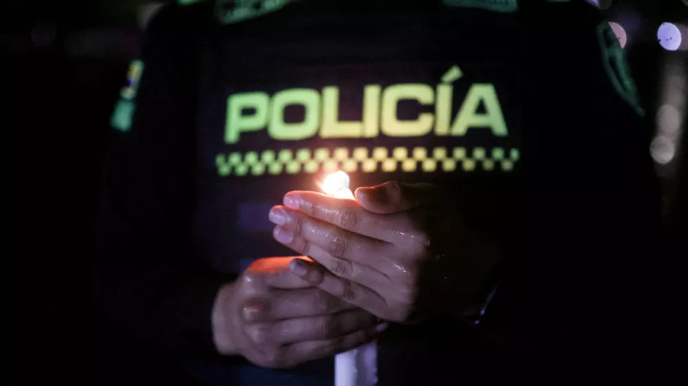 A police officer holds a candle during a tribute to the victims of a military plane crash that occurred shortly after takeoff in Puerto Leguizamo, in Bogota, Colombia, March 25, 2026. REUTERS/Luisa Gonzalez   TPX IMAGES OF THE DAY