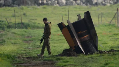 FILE - An Israeli soldier stands next to a fragment of a missile fired from Iran and intercepted by Israeli air defense system embedded in an open field in the Israeli-controlled Golan Heights, March 19, 2026. (AP Photo/Ohad Zwigenberg, File)