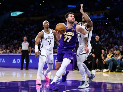 Mar 27, 2026; Los Angeles, California, USA; Los Angeles Lakers guard Luka Doncic (77) drives against Brooklyn Nets guards Ochai Agbaji (30) and Terance Mann (14) during the second half at Crypto.com Arena. Mandatory Credit: William Liang-Imagn Images