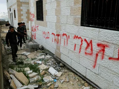 Boys stand near graffiti that reads, "Revenge. Death to Arabs", which Palestinians say was written by Israeli settlers, near Hebron in the Israeli-occupied West Bank, March 30, 2026. REUTERS/Yosri Aljamal