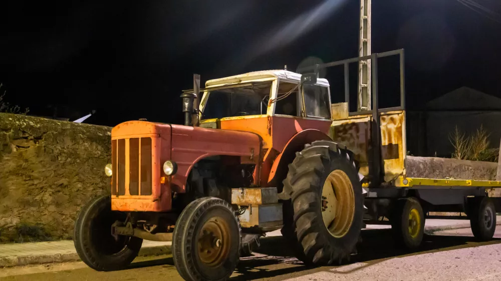 Night photograph of an old red tractor under artificial lighting.