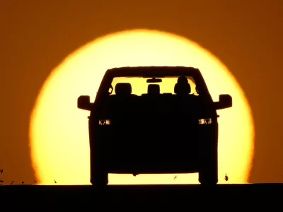 A motorist is silhouetted by the setting sun as the region hit a high temperature to tie a record for the hottest day in March in the area, Thursday, March 26, 2026, in Lenexa, Kan. (AP Photo/Charlie Riedel)