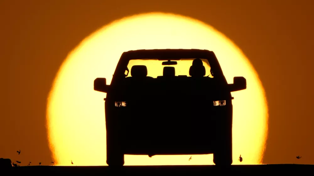 A motorist is silhouetted by the setting sun as the region hit a high temperature to tie a record for the hottest day in March in the area, Thursday, March 26, 2026, in Lenexa, Kan. (AP Photo/Charlie Riedel)