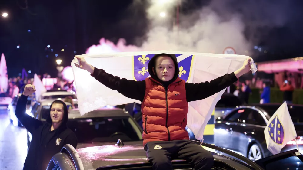 Bosnian fans wave flags as they celebrate after the Bosnian national team qualified for the World Cup by winning a penalty shootout against Italy, in Zenica, Bosnia, Wednesday, April 1, 2026. (AP Photo/Armin Durgut)