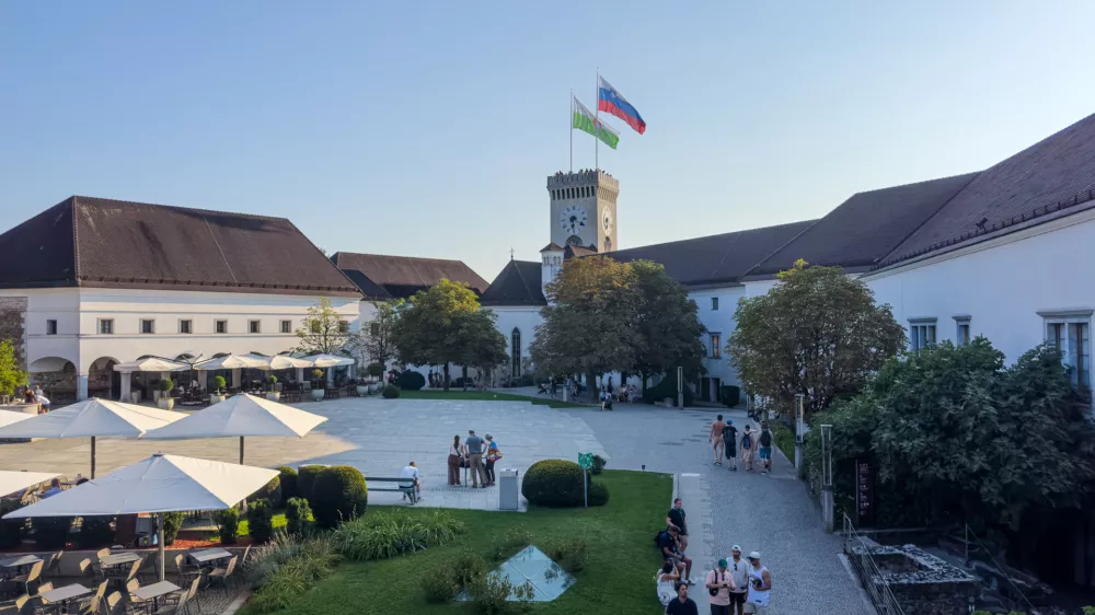 Ljubljana, Slovenia - August 11, 2025: Courtyard of historical and symbolic Ljubljana Castle with national and city flags flying high on the tower, Ljubljana, Slovenia. Tourist attraction.