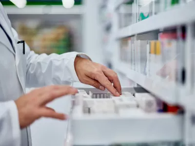 Male pharmacist choosing a medicine from the drawer, side view.