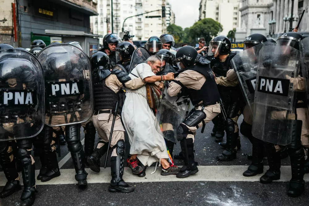 South America | Singles | Milei's ArgentinaPolice detain Father Jorge 'Chueco' Romero during a pensioners' protest. Members of the Option for the Poor clergy have joined weekly demonstrations against pension freezes and cuts to essential medical coverage. Buenos Aires, 14 May 2025. In Argentina, aggressive austerity measures aimed at curbing 200% inflation have plunged older people into a desperate struggle for survival. With the minimum pension hovering around $300 &ndash; below half the estimated basic cost of living &ndash; many retirees are forced to ration food and forgo essential medical treatmentsPhotograph: Tadeo Bourbon, for Revista Mu/World Press Photo 2026