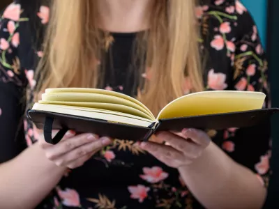 Young blonde girl with an open book in her hand, reading a book