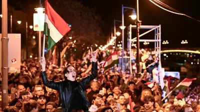 A man waves a Hungarian flag as he celebrates in the streets after the announcement of partial results of the Hungarian parliamentary election in Budapest, Hungary, Sunday, April 12, 2026. (AP Photo/Denes Erdos)
