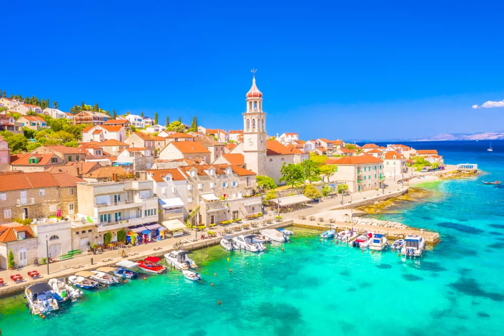 Charming view of old church bells and terracotta rooftops in the peaceful Mediterranean fishing village of Sutivan on Brac Island, Croatia, with traditional stone houses and coastal scenery