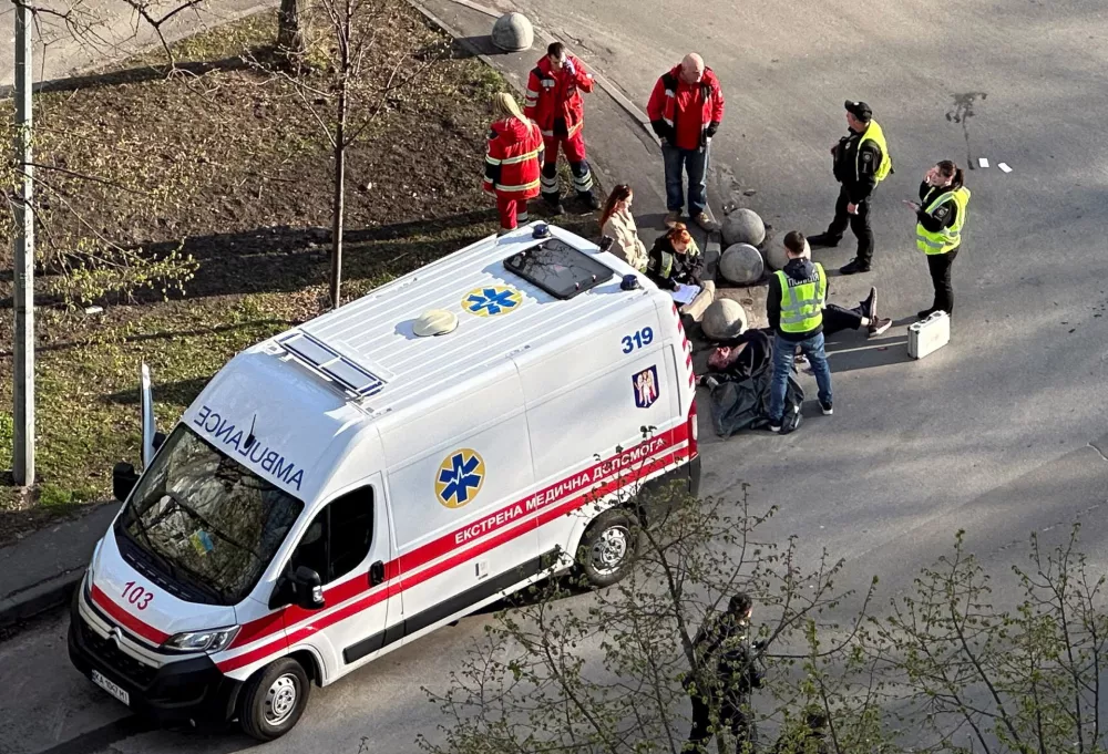 SENSITIVE MATERIAL. THIS IMAGE MAY OFFEND OR DISTURB. An ambulance and police officers work next to a body at the site of a shooting incident, in Kyiv, Ukraine, April 18, 2026. Picture taken with a mobile phone. REUTERS/Stringer