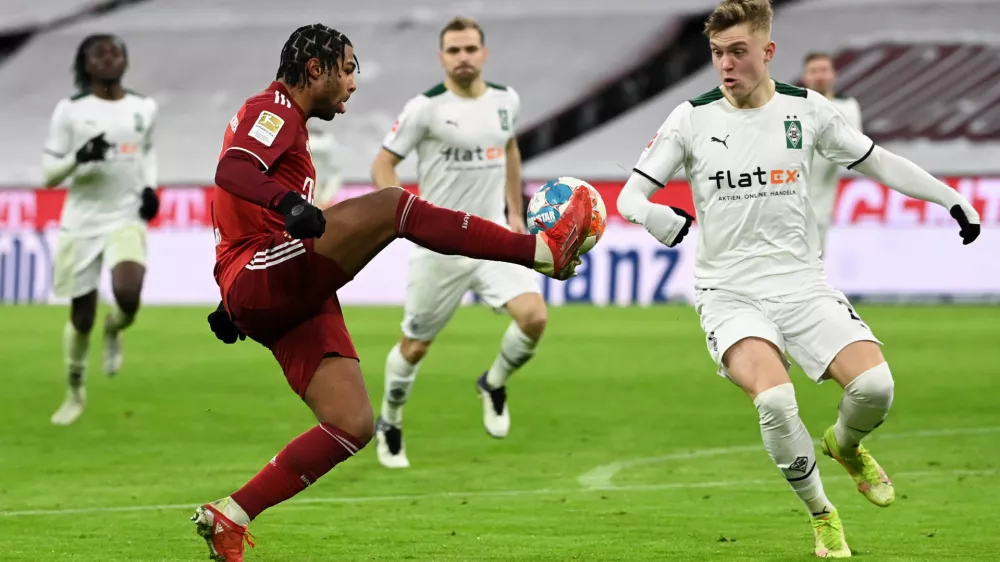 07 January 2022, Bavaria, Munich: Munich's Serge Gnabry (L) and Moenchengladbach's Luca Netz battle for the ball during the German Bundesliga soccer match between Bayern Munich and Borussia Moenchengladbach at Allianz Arena. Photo: Sven Hoppe/dpa - IMPORTANT NOTICE: DFL and DFB regulations prohibit any use of photographs as image sequences and/or quasi-video.