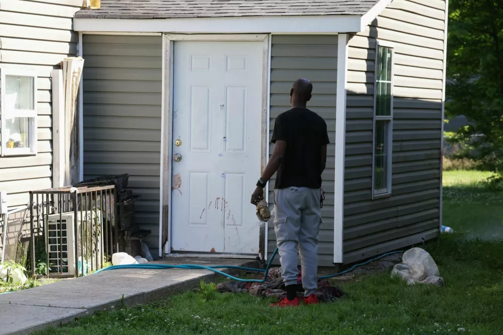 SENSITIVE MATERIAL. THIS IMAGE MAY OFFEND OR DISTURB A man uses a water hose to wash blood from a door after children, with ages ranging from 1 to 14, were killed in a mass shooting incident described as domestic violence, in Shreveport, Louisiana, U.S. April 19, 2026. REUTERS/Kevin Bartram