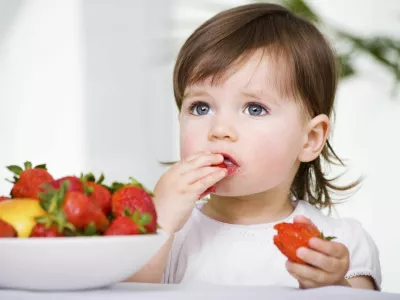 a little girl eating strawberries