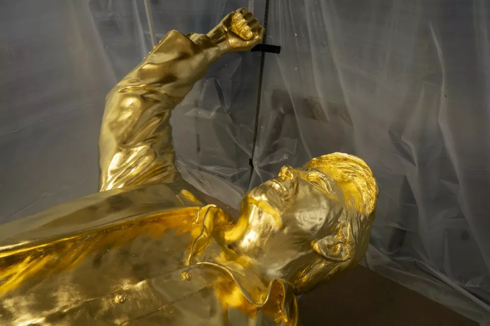 The bust portion of a 15-foot bronze statue of US President Donald Trump, coated in gold leaf, lies on its back in the studio of sculptor Alan Cottrill in Zanesville, Ohio on February 5, 2026. Lying on its back at an Ohio sculpture studio, the 15-foot tall (4.6 meter) gold-leafed statue of US President Donald Trump dubbed "Don Colossus" by its creators is, perhaps, not quite at its best. The massive bronze work, slated to stand two-storeys tall once installed on a 6,000-pound (2,720-kg) base, depicts a defiant Trump raising his fist in the moments after he survived an assassination attempt in July 2024. But the $360,000 statue, commissioned by cryptocurrency entrepreneurs and backers of then-candidate Trump, has waited more than a year to be erected, partly because sculptor Alan Cottrill has yet to get paid.,Image: 1072712577, License: Rights-managed, Restrictions: To go with AFP story by Eli HILLER and Asad HASHIM: "'Don Colossus': Golden Trump statue crippled by crypto pay dispute", Model Release: no