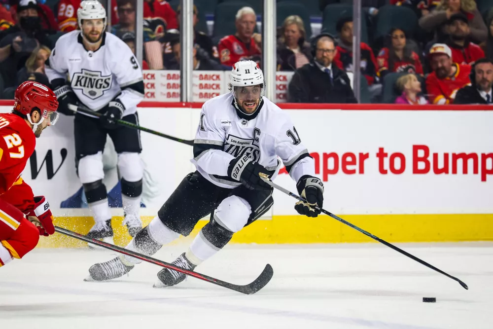 Apr 16, 2026; Calgary, Alberta, CAN; Los Angeles Kings center Anze Kopitar (11) controls the puck against Calgary Flames right wing Matt Coronato (27) during the first period at Scotiabank Saddledome. Mandatory Credit: Sergei Belski-Imagn Images