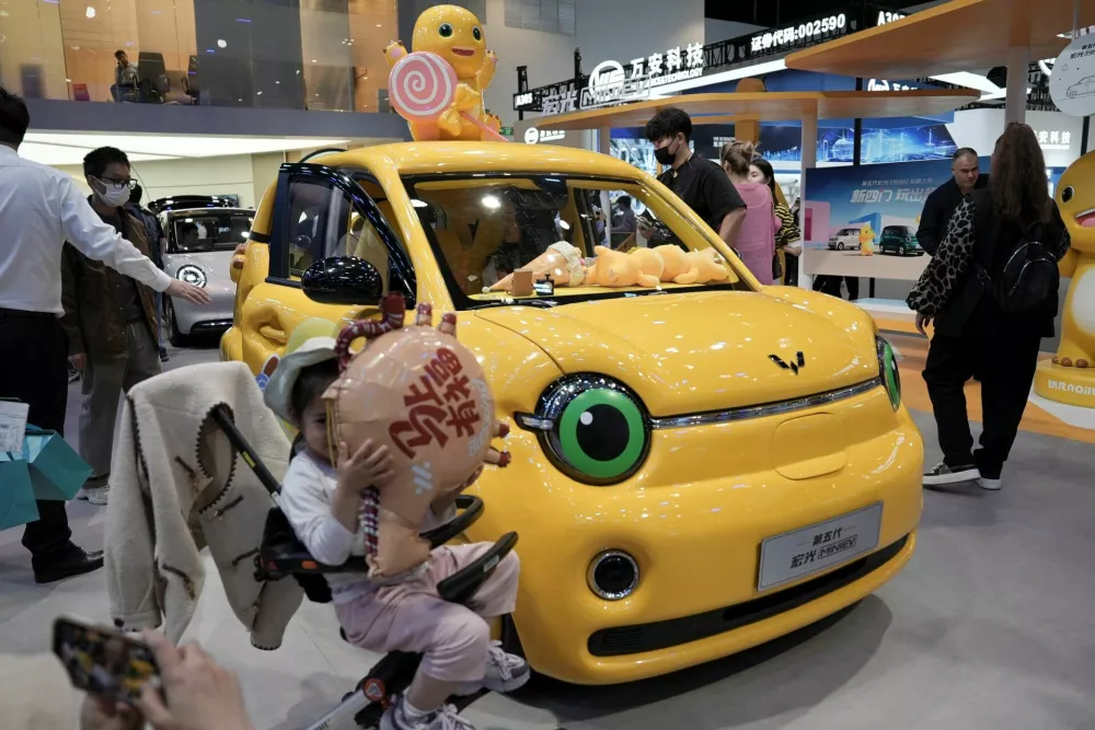 A child poses in front of a Wuling Hongguang MiniEV electric vehicle displayed at the Beijing International Automotive Exhibition, or Auto China, in Beijing, China April 26, 2026. REUTERS/Xiaoyu Yin