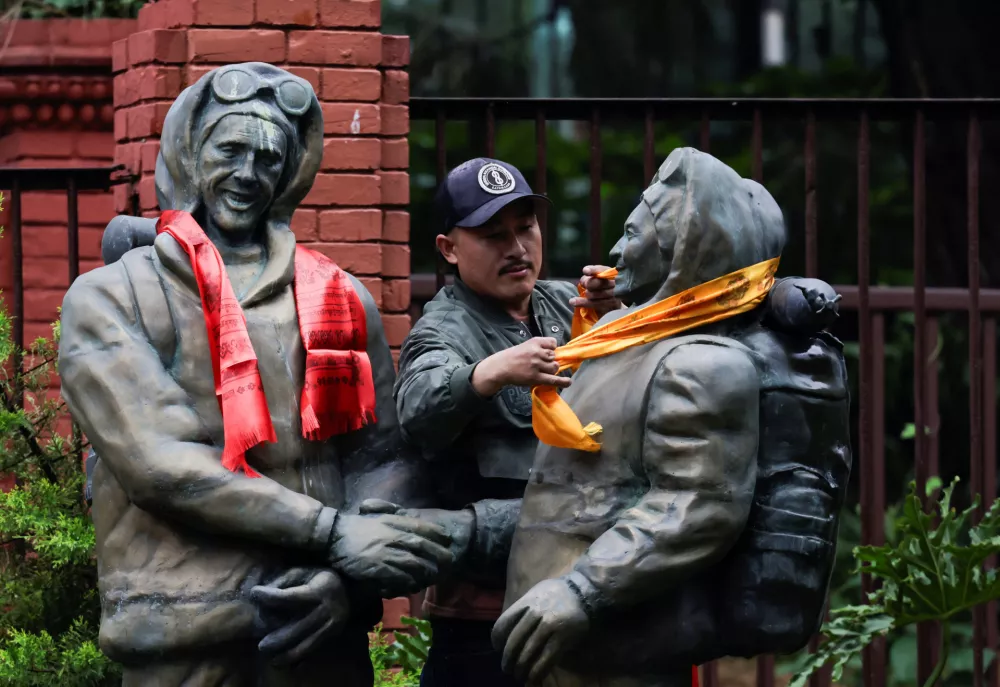 Temba Tsheri Sherpa, 41, who became the youngest person to climb Mount Everest at the age of 16, places a ceremonial scarf on the statue of Edmund Hillary and Tenzing Norgay Sherpa, the first mountaineers to conquer Mount Everest in 1953, during the anniversary of their ascent and to mark International Everest Day in Kathmandu, Nepal, May 29, 2026. REUTERS/Navesh Chitrakar