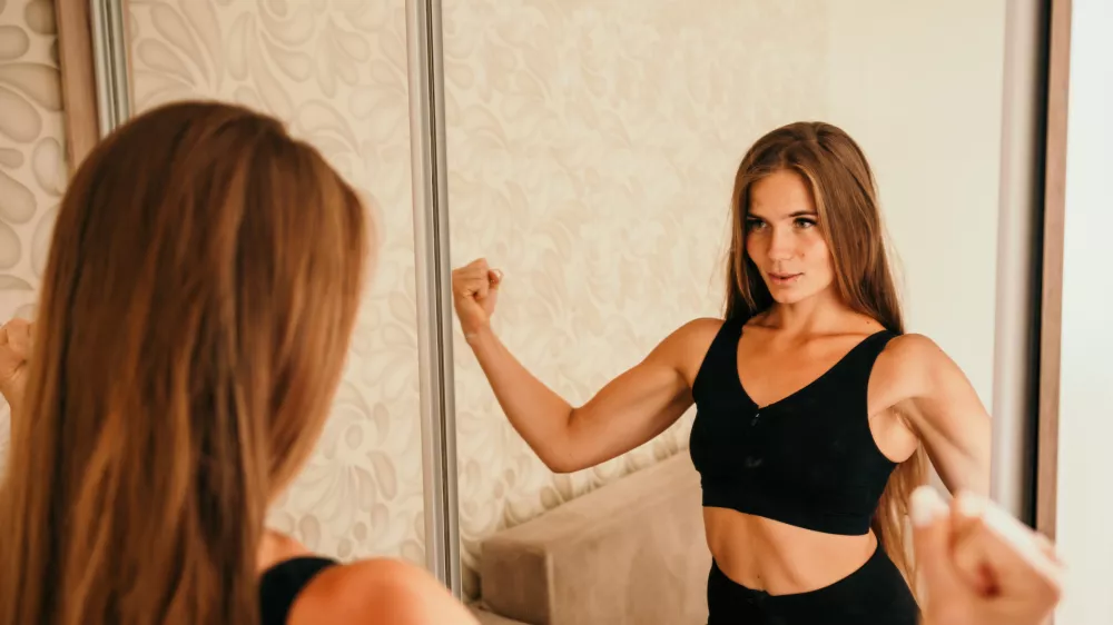 Young woman with long hair, fitness instructor in black sportswear, doing stretching and pilates on yoga mat at home. Female fitness yoga routine concept. Healthy lifestyle harmony and meditation