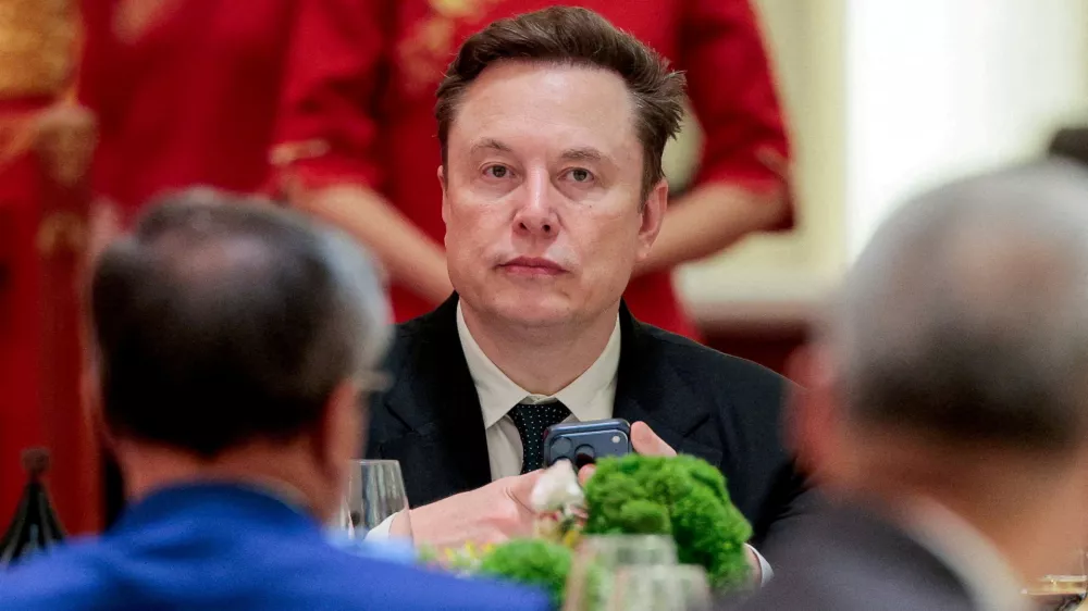 FILE PHOTO: Tesla CEO Elon Musk holds a mobile phone as he arrives to attend a state banquet with U.S. President Donald&nbsp;Trump and Chinese President Xi Jinping at the Great Hall of the People in Beijing, China, May 14, 2026. REUTERS/Evan Vucci//File Photo