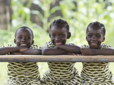 Three African children proudly sitting in their desk at school in Bamako, Mali. Candid outdoor shot of one boy and two girls learning their lessons at school.