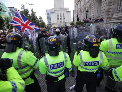 03 August 2024, United Kingdom, Liverpool: Police officers face protesters, following the stabbing attacks on Monday in Southport, which three young children were killed. Photo: James Speakman/PA Wire/dpa